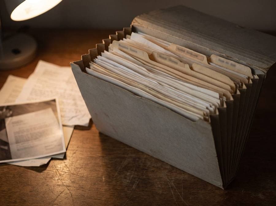 An expanded case file on a desk under a lamp.